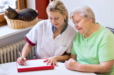 senior woman and caregiver writing on the table